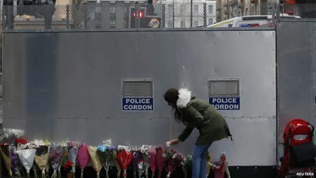 A woman places a candle near the scene