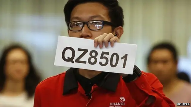 A Changi Airport staff holds up a sign to direct possible next-of-kins of passengers of AirAsia flight QZ 8501 from Indonesian city of Surabaya to Singapore, at Changi Airport in Singapore on 28 December, 2014