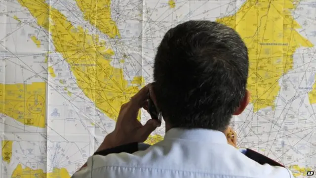 An airport official checks a map of Indonesia at the crisis center set up by local authority for the missing AirAsia flight QZ8501, at Juanda International Airport in Surabaya, East Java, Indonesia on Sunday, 28 December, 2014