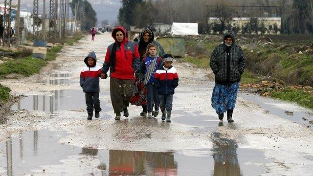 Syrian refugees walk along a makeshift settlement in Bar Elias in the Bekaa valley January 5, 2015