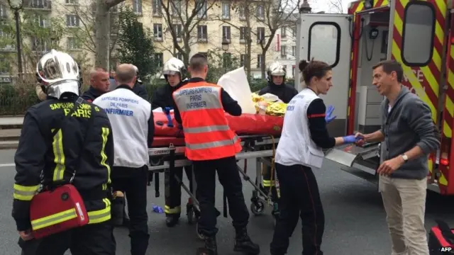 An injured man is carried away by the emergency services near the offices of Charlie Hebdo