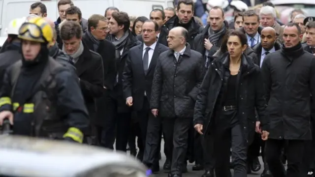 French President Francois Hollande (centre left) flanked by Interior Minister Bernard Cazeneuve (right) walk outside the French satirical newspaper Charlie Hebdo's office in Paris