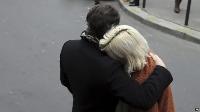 People stand outside the French satirical newspaper Charlie Hebdo's office after the shooting