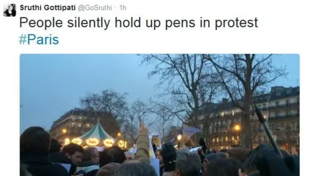 People in Paris hold up their pens in protest