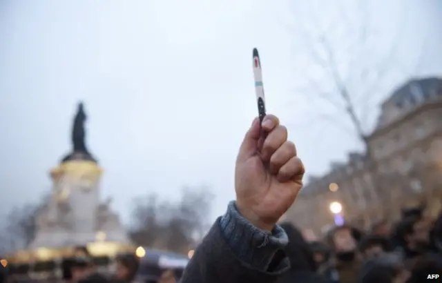 A man raises a pen during a rally in support of the victims of today"s terrorist attack on French satyrical newspaper Charlie Hebdo at the Place de la Republique in Paris, on January 7, 2015