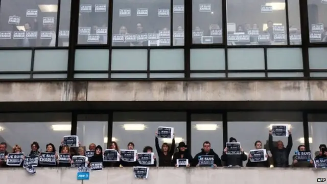 AFP staff hold up "Je Suis Charlie" signs as they observe a one minutes silence