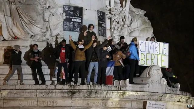 People hold a placard reading in French 'Charlie Berte' (CharLiberty), standing on the pedestal of a statue on the Place de Republique (Republic square) in Paris, on January 8, 2015