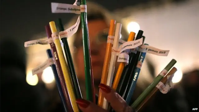 A woman holds pencils on January 8, 2015 in Turin during a rally in remembrance of the victims of an attack against Charlie Hebdo satirical weekly which killed 12 people in Paris yesterday.