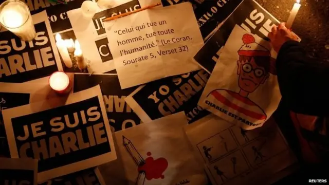 A woman places a candle over signs during a vigil for the victims of the shooting at the Paris offices of Charlie Hebdo, outside the French embassy in Mexico City