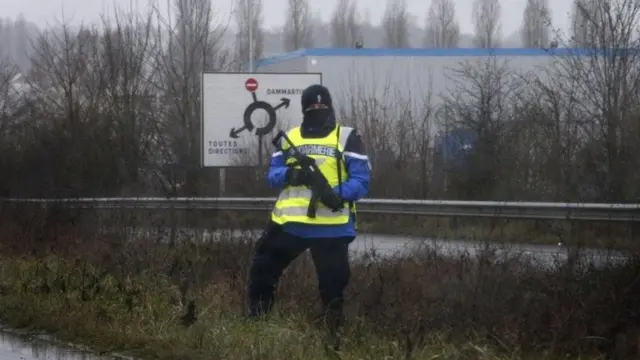 A police officer stands along a road near an industrial area where the suspects in the shooting attack at the satirical French magazine Charlie Hebdo headquarters are reportedly holding a hostage, in Dammartin-en-Goele, some 40 kilometres north-east of Paris, France, 09 January 2015.