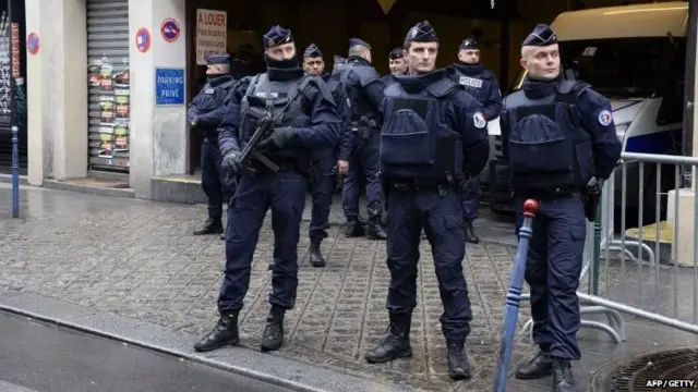 French police officers stand guard in front of the headquarters of French newspaper Liberation as editorial staff of French satirical weekly newspaper Charlie Hebdo and Liberation meet, on January 9, 2015 in Paris