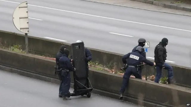 Hooded police officers cross the closed ring road that circles Paris near an hostage-taking situation at a kosher market in Paris on 9 January 2015.