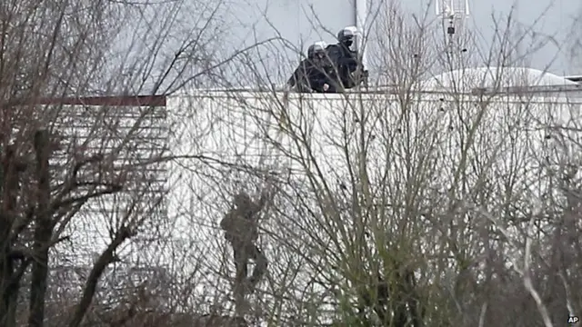 Police officers take position atop a building in Dammartin-en-Goele, northeast of Paris, where the two brothers suspected in a deadly terror attack were cornered, 9 January 2015.