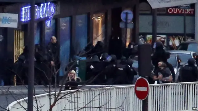 Members of the French police special forces evacuate the hostages including a child (R) after launching the assault at a kosher grocery store in Porte de Vincennes, eastern Paris, on 9 January 2015