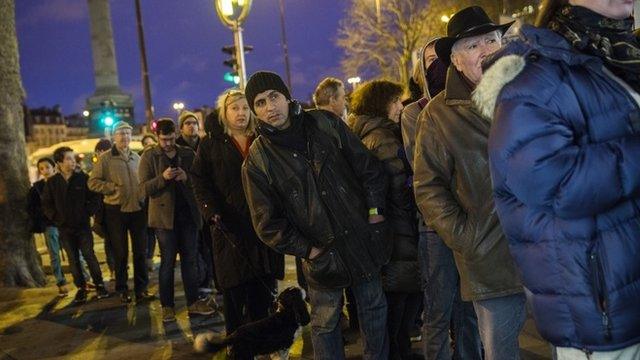 Members of the public queue at a newspaper kiosk in Paris