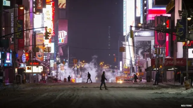 People cross a car-free snow covered seventh avenue in midtown Manhattan in New York City early on 27 January 2015