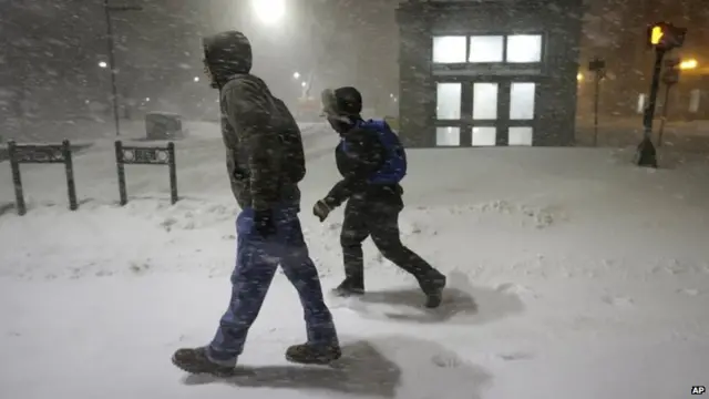 Medical researchers Chris Dubois, of Boston, left, and Caitlin DuBois, of Rochester, N.H., behind, not related, walk to work early 27 January 2015