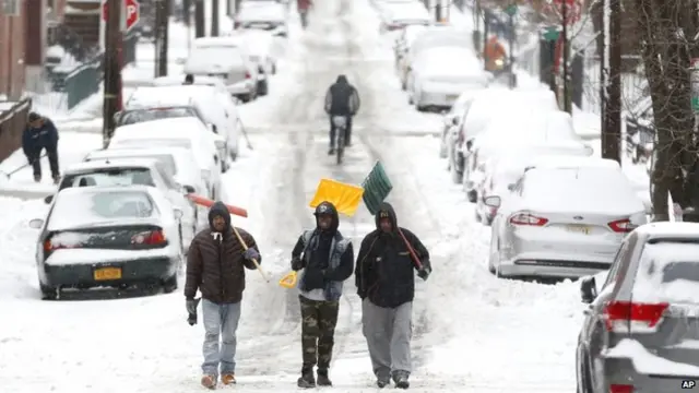 Men carry shovels as they walk on a snow covered road after an overnight snowstorm, Tuesday, Jan. 27, 2015, in Hoboken, N.J.