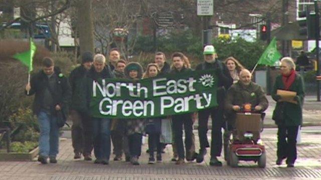 Green Party members marching with banner