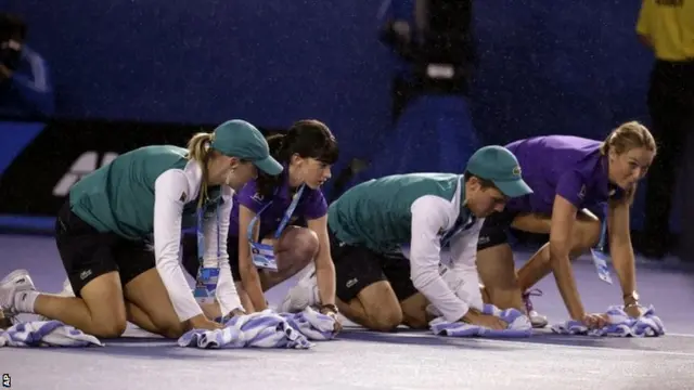 Ground staff drying the court