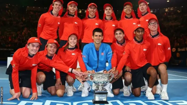 Novak Djokovic poses with ball boys and girls