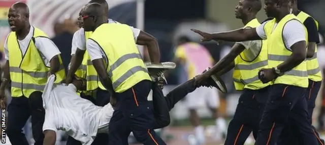 A spectator is carried off the pitch after trying to attack the referee