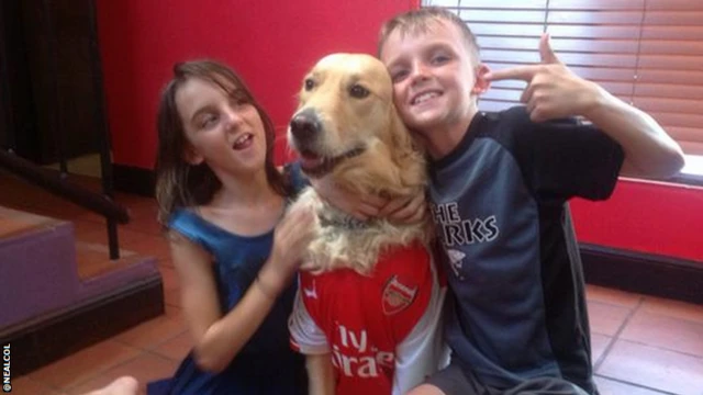 A dog poses with children wearing an Arsenal shirt