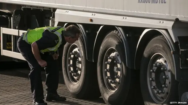 Police officer checking under lorry