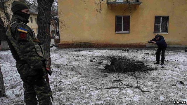 A Ukrainian serviceman guards the street next to the remains of a rocket shell in the town of Kramatorsk, eastern Ukraine 10 February, 2015