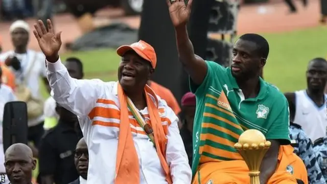 Ivorian President Alassane Ouattara and Ivory Coast captain Yaya Toure wave at the crowd