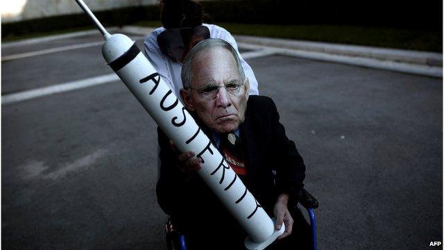 A protester wearing a mask depicting German Finance Minister Wolfgang Schaeuble holds a syringe reading "austerity" during an anti-austerity demonstration on 15 February 2015