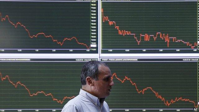 An employee of the Stock Exchange walks next to a display showing stock price movements in Athens on 28 January 2015