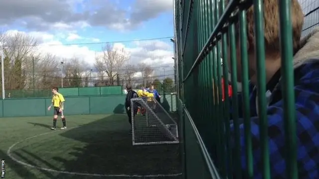 People's Cup player being carried off the pitch helped by a member of the other team