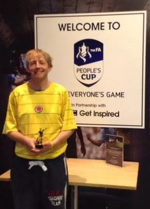 Player with trophy in front of People's Cup welcome board