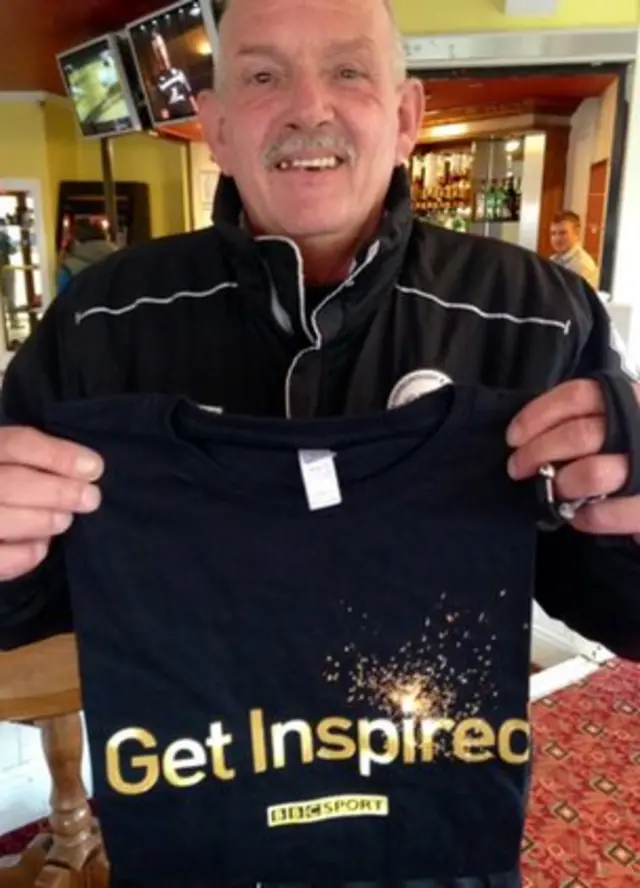 older man holding up a Get Inspired T-shirt