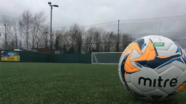 A football in the foreground, 5-a-side venue in the background