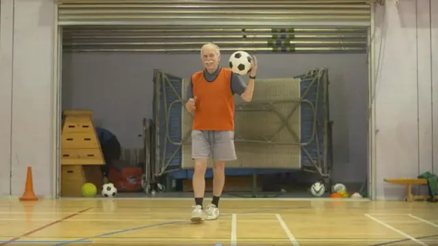 Man wearing bib holding a football on his shoulder