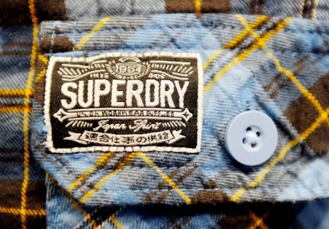 The Superdry logo on a man's shirt.