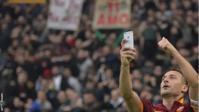 Roma's forward Francesco Totti celebrates by taking a 'selfie' with fans after scoring a second goal during the Italian Serie A match