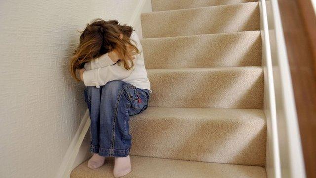 Library image of young girl sitting on a staircase, covering her face