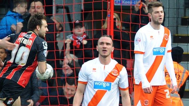 Brett Pitman wheels away to celebrate with Blackpool looking disconsolate.