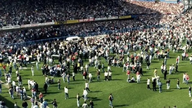 fans on pitch plus ambulance