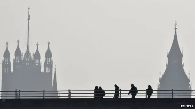 People walk across Waterloo Bridge in front of The Houses of Parliament