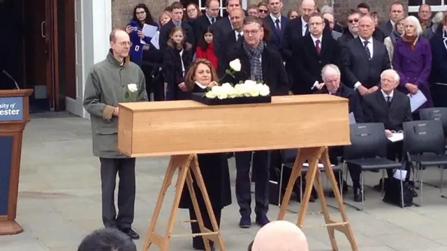 Relatives place roses on the coffin