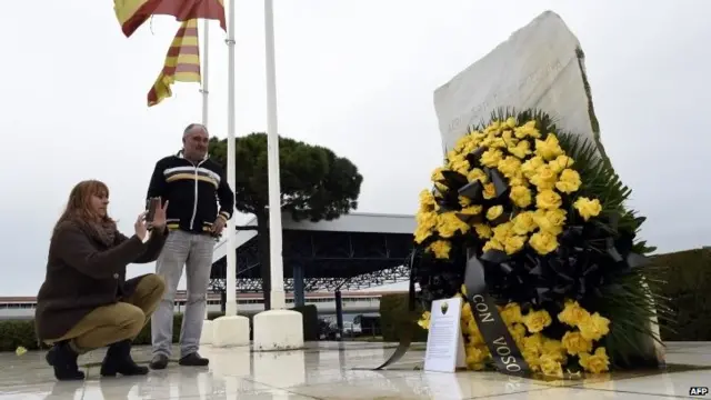 Employees of Barcelona's El Prat airport take pictures of a wreath of flowers displayed in honour of the victims of the crash