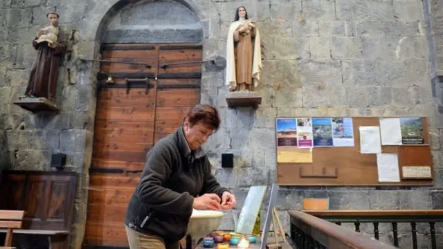 A woman lights a candle inside a church in the town of Seyne-les-Alpes, near the crash site (26 March 2015)