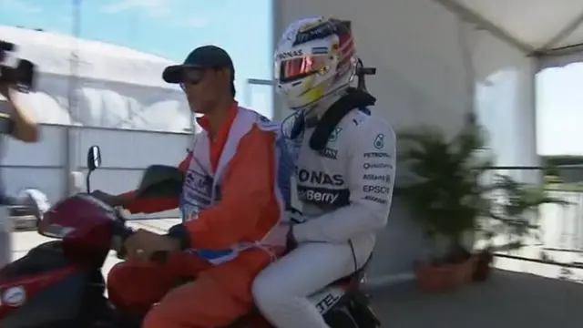 Lewis Hamilton sits on the back of a steward's scooter