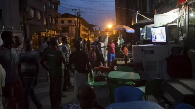 People watch election news coverage on television at a street in Lagos, Nigeria, March 30, 2015.