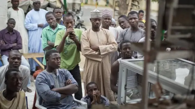 Nigerian men watch as the election commission announces electoral results for certain states, on a television at an outdoor butchery in Kano, northern Nigeria Tuesday, 31 March 2015