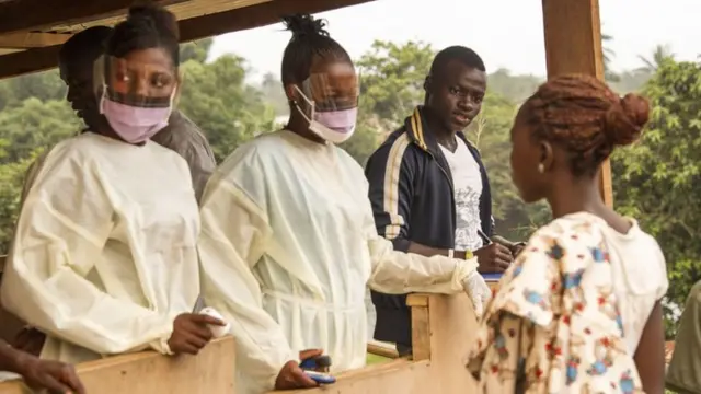 Sierra Leone health officials check passengers transiting at the border crossing with Liberia